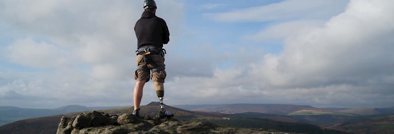 Man with prosthetic leg standing on top of mountain