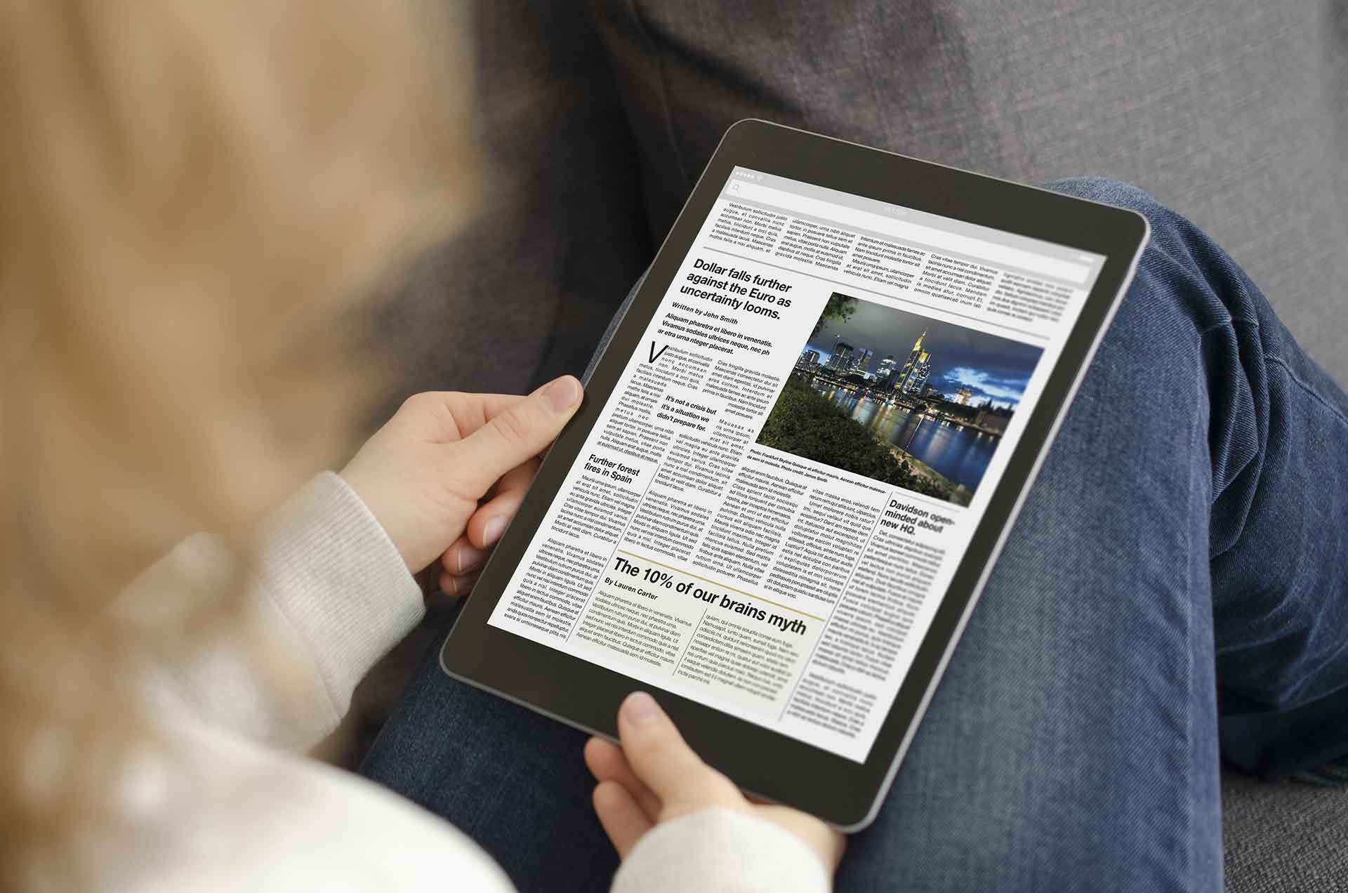 Person holding iPad showing news article